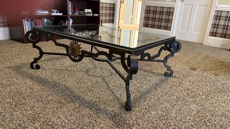 Black iron coffee table with glass top and brass sun like embellishments